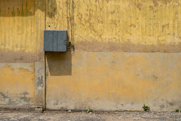 Texture of old yellow vintage wall of industrial factory with electric cable