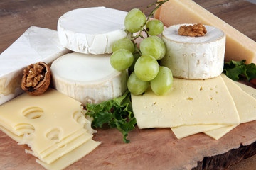 Cheese platter with different cheese on brown wooden plate