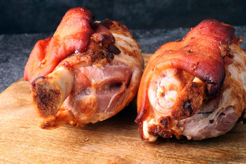 Smoked ham hock with herbs and spices on wooden plate.