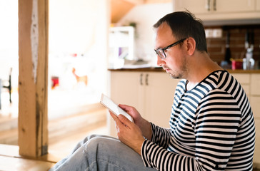 Young man in striped t-shirt with tablet at home.