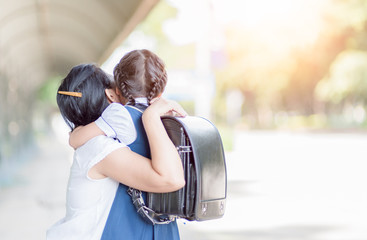 mother hugging daughter in uniform student