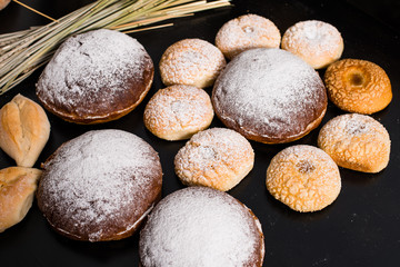delicious baked goods, traditional Italian bread Ciriola Romana and wheat on a dark background