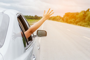 Woman hand in the car relaxing and happy traveler on the road