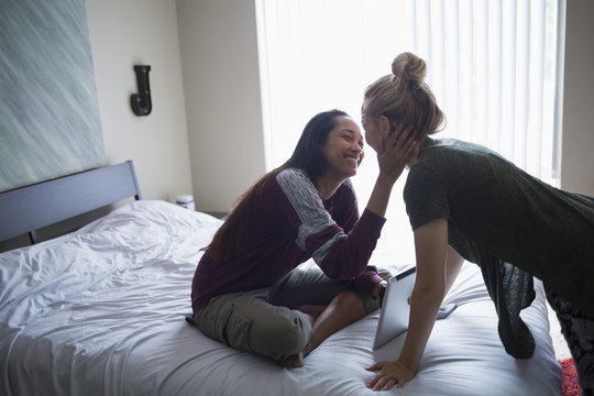 Smiling young lesbian couple on bed with digital tablet at home