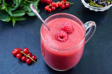 Berry smoothies in a glass mug on a black background.
