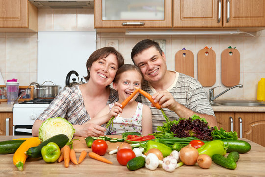 family cooking in kitchen interior at home, fresh fruits and vegetables, healthy food concept, woman, man and children