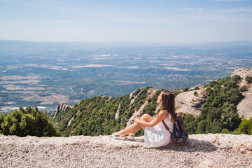 Fototapeta na wymiar Young woman with backpack enjoying the view in Montserrat mountain on a hot summer day