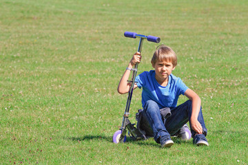 Fototapeta premium Boy sitting on a scooter in the park