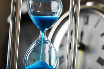 Time is passing. Blue hourglass close up