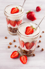 Breakfast with chocolate balls corn flakes, sliced strawberry on white wood board.