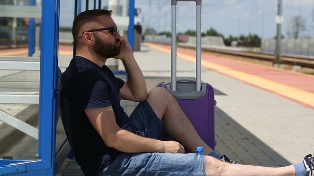 Man answers cellphone while sitting on the platform and looks really angry
