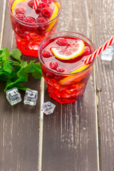 Summer drink with raspberries, lime and ice on a old wooden table