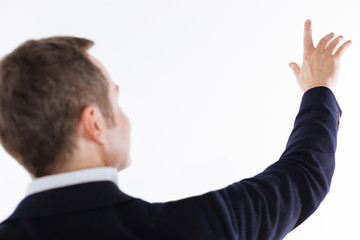 Delicate interested gentleman reaching for something above him