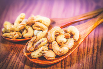 Roasted cashew nuts on a wooden spoon.Roasted salted cashew nuts on white background. Healthy food, cashews rich in heart friendly fatty acids. Cashew nuts as food background.