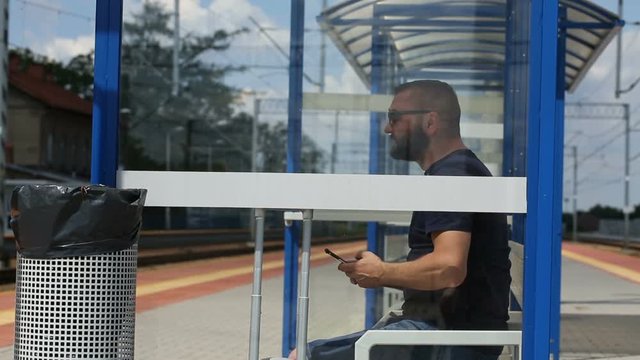 Man texting messages on smartphone while sitting on the train stop
