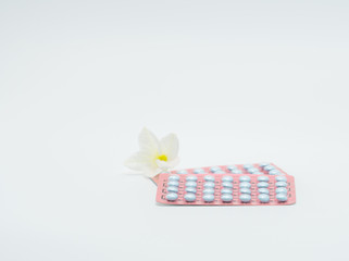 Two blister packaging of hormones for treatment menopausal women and flower on white background