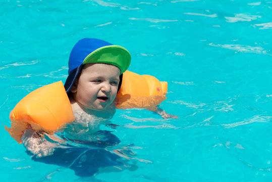 Baby swimming in the blue pool water.