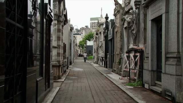 Man walking narrow corridor between tombs at Recoleta cemetery in Buenos Aires, Argentina
