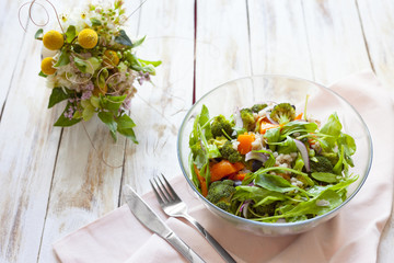 Warm vegetable salad with pumpkin, pearl barley and spinach on old wooden white background.