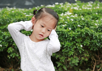 Child girl shutting down her ears, holding her hands to cover ears not to hear.