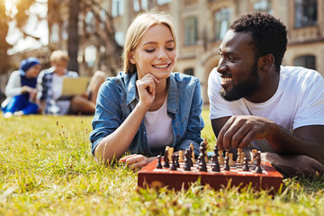 Positive pretty woman teaching her friend playing chess