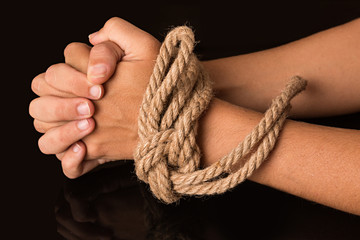 Manos de mujer atadas con una cuerda.