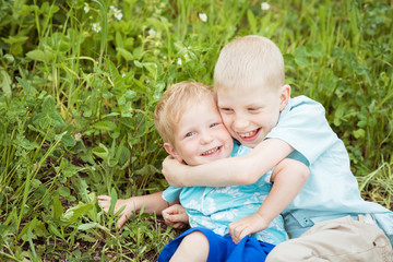 Two child boy hugging on the grass
