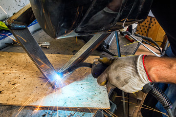 man welds with a welding machine - obrazy, fototapety, plakaty