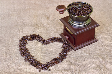 Coffee grinder full of roasted coffee beans and coffee beans heart shape - from the top