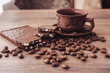 roasted coffee beans with chocolate and nuts on a wooden surface.