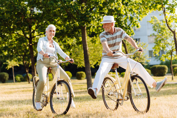 Positive delighted couple while cycling in park