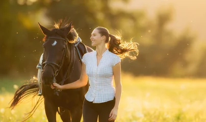 Deurstickers Young woman running with her horse in evening sunset light © Jag_cz