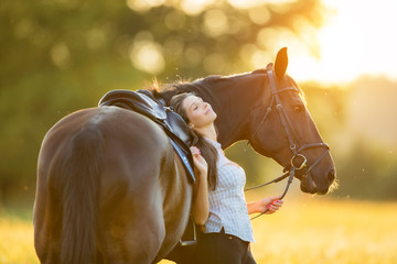 Young woman with her horse in evening sunset light