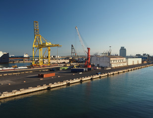 Fototapeta na wymiar harbour in Livorno, Italy with cranes and industrial buildings in golden morning light