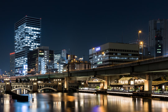 Modern office buildings and car bridge in Osaka at night illuminated with street lamps