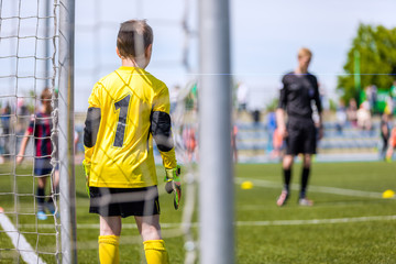 Soccer goalkeeper of youth team. Football tournament for kids. Children kicking soccer game. Soccer pitch in the background
