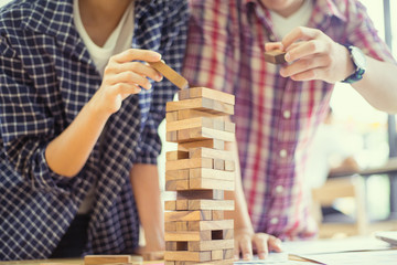 business people playing wooden tower game