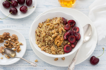 Healthy delicious vegan breakfast. Quinoa with fresh cherries, walnuts and honey on the blue background