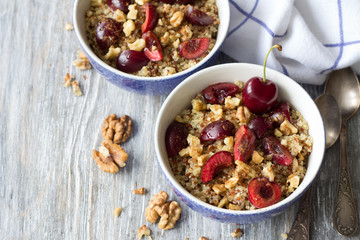 Healthy delicious vegan breakfast. Quinoa with fresh cherries, walnuts and honey on the blue background