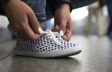 Fototapeta premium Girl ties up shoelaces on sneakers