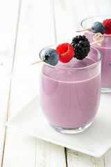 Healthy berry smoothie in glass on white wooden table

