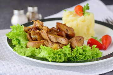 Fried bull testicles with cream and herbs served with mashed potato on a white plate on an abstract background. Healthy food concept