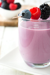 Healthy berry smoothie in glass on white wooden table
