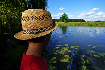 Boy with the heat is fishing on a lake
