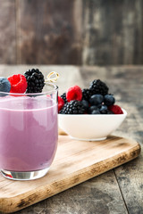 Healthy berry smoothie in glass on wooden table
