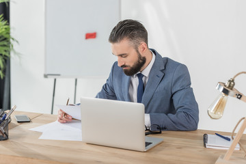 portrait of focused businessman doing paperwork at workplace in office