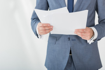 partial view of businessman holding papers in hands in office