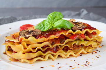 Vegetarian lasagna with mushrooms, onions, olives and tomato sauce on a white plate. Healthy eating concept. Mediterranian lifestyle