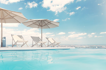 Fototapeta na wymiar Swimming pool with deck chairs, umbrellas, sky