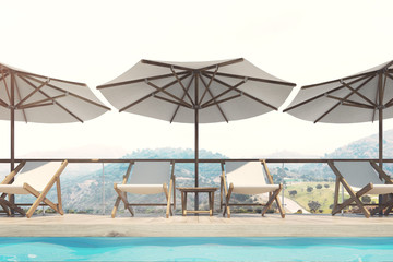 White deck chairs, umbrellas, mountains, closeup